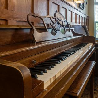A classic wooden piano with a row of gleaming keys in a warmly lit room.