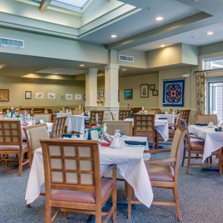 An elegant dining area with tables set for guests, featuring a skylight and tasteful decor.