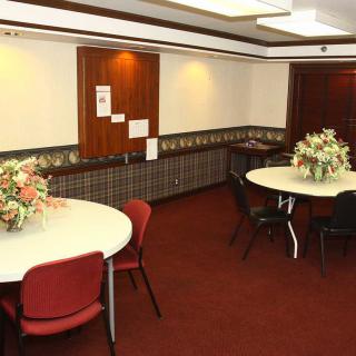 A well-arranged meeting room with round tables and flower decorations.