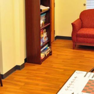A cozy living room with a bookshelf, red couch, and wooden flooring.