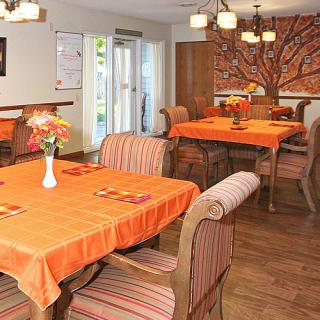 A cozy dining area featuring tables with orange tablecloths and floral decorations.