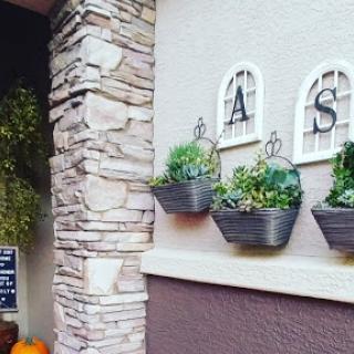 Charming exterior with hanging planters and decorative letters.