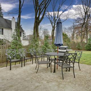 A backyard patio with a set of metal furniture including a table, chairs, and an umbrella.