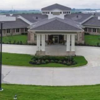 A large building with a central entrance and surrounding green lawn.
