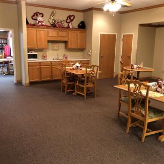 A cozy dining area with wooden tables and chairs, adjacent to a small kitchen space.