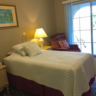 A cozy bedroom with a single bed, armchair, and a window.