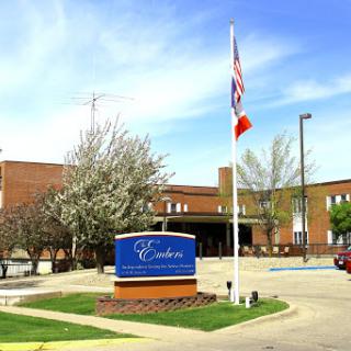 Exterior view of a building with a sign and flags, surrounded by trees.