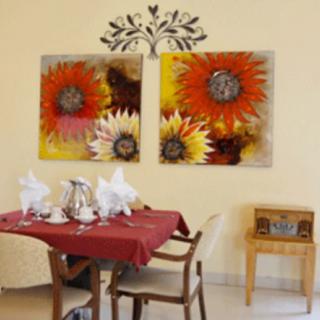 A cozy dining area featuring vibrant floral wall art, a red tablecloth, and elegant table settings.