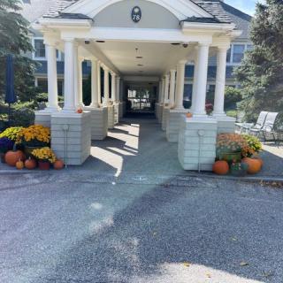 A covered entrance with columns decorated with pumpkins and flowers.