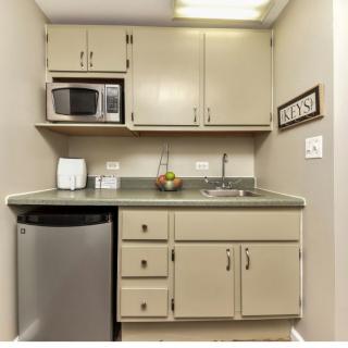 A compact kitchenette with a microwave, sink, and cabinets.