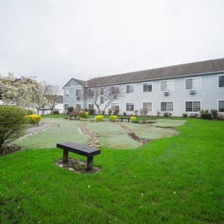 A well-maintained garden with a bench in front of a residential building on an overcast day.