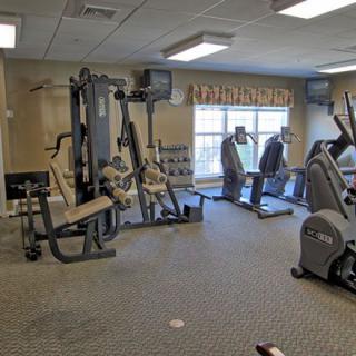 A well-equipped gym with various exercise machines, including treadmills, stationary bikes, and a multigym machine.