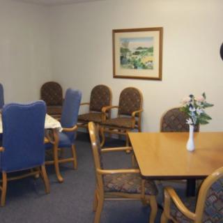 A small meeting room with tables and chairs, adorned with a framed artwork on the wall.