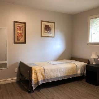 A minimalist bedroom with a single bed, nightstand, and decorative artwork on the wall.