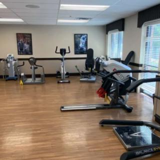 A well-equipped gym with various exercise machines and ample natural light.