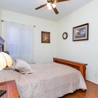 A cozy bedroom with a bed, ceiling fan, and artwork on the walls.