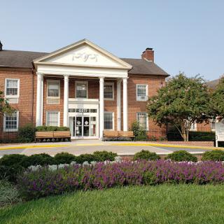 A charming brick building with a classic architectural design, surrounded by well-maintained landscaping and vibrant flowers.