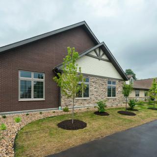 A modern house with a brick and stone exterior, surrounded by landscaped greenery and a paved driveway.
