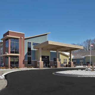 A modern commercial building with a welcoming entrance, situated in a clear blue sky.