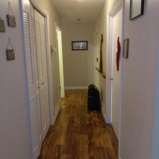 A well-lit hallway with wooden flooring and decorated walls.