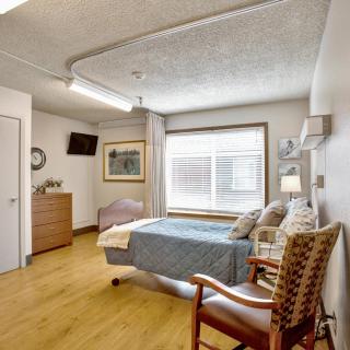 A hospital room featuring a single bed, a television, and a window providing natural light.