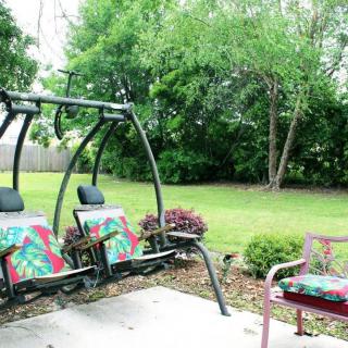 A peaceful backyard with a swing and chairs, surrounded by greenery.