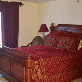 A cozy bedroom with a wooden bed frame, red bedding, and matching curtains and lamp.