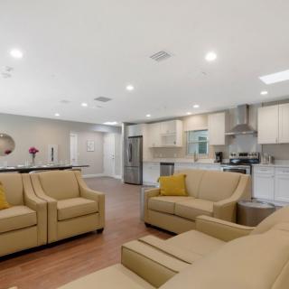 A modern open-concept living room and kitchen featuring beige sofas and recessed lighting.