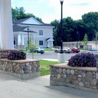 A scenic view of a residential area with a stone wall and landscaped plants.