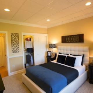 A modern, cozy bedroom featuring a stylish bed with dark bedding, soft lighting, and elegant decor.