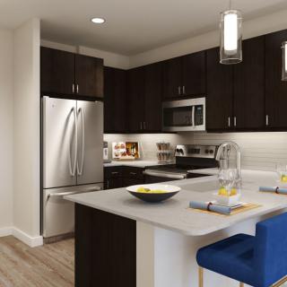 A modern kitchen featuring dark cabinets, stainless steel appliances, and a central countertop island with bar stools.