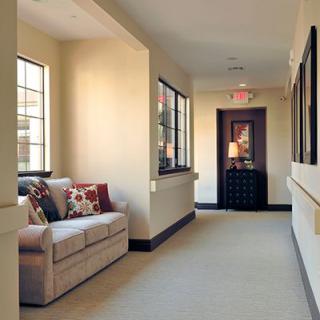 A cozy hallway with a sofa and decorative pillows near large windows.