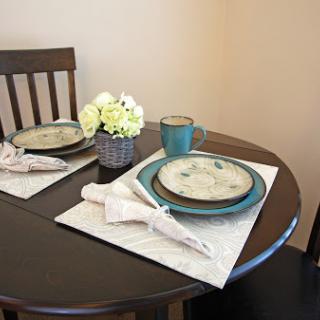 A beautifully arranged dining table featuring elegant plates, a coffee mug, and a charming floral centerpiece.