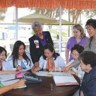 A group of healthcare professionals engaged in a collaborative discussion around a table.