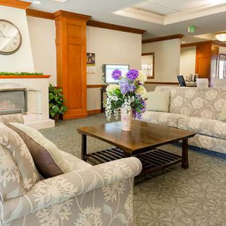 A cozy living room with patterned sofas, a wooden coffee table with a floral arrangement, and a fireplace.