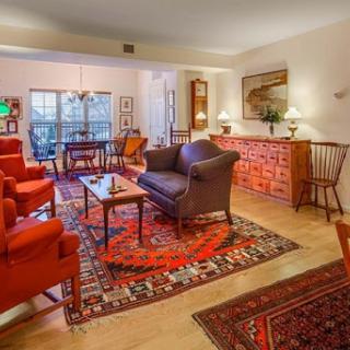 A beautifully arranged living room featuring red upholstered chairs, a dark sofa, and an elegant rug, creating a warm and inviting atmosphere.