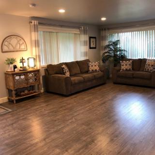 A cozy living room with two sofas, warm lighting, and hardwood floors.