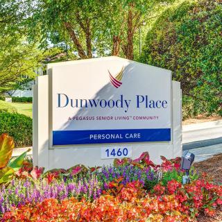 Entrance sign for Dunwoody Place surrounded by colorful flowers.
