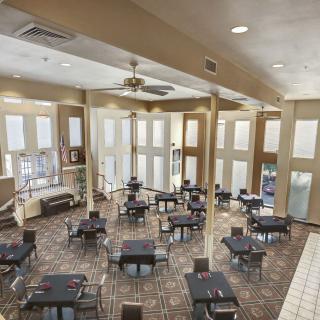 Spacious dining area with neatly arranged tables and chairs, featuring large windows for natural light.