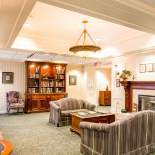 A cozy living room with traditional decor, featuring comfortable sofas, a well-stocked bookshelf, and a warm fireplace.