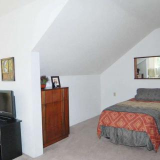 A cozy attic bedroom with a bed, dresser, and slanted ceiling.