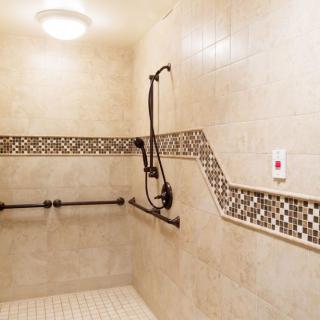 A spacious, accessible shower with tiled walls and grab bars.