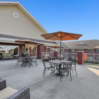 An outdoor patio area with tables, chairs, and umbrellas next to a building.