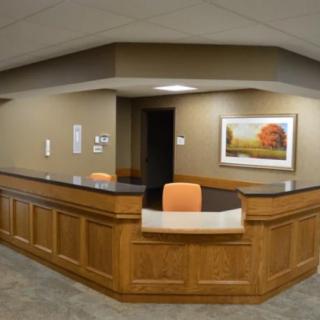 An office reception desk with a painting on the wall.