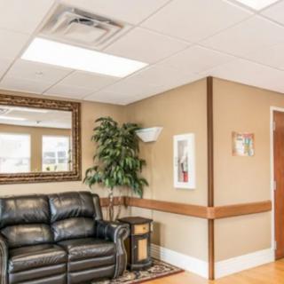 A cozy waiting room with a leather sofa, a large mirror, and decorative plants.