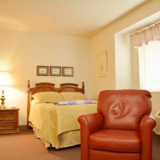 A cozy bedroom with a bed, armchair, and warm lighting.