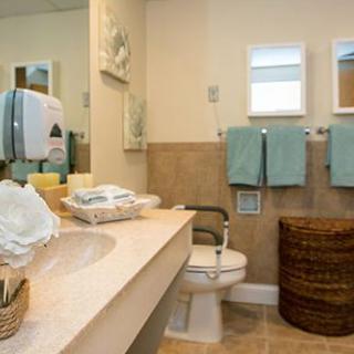 A well-organized bathroom featuring a sink, toilet, and neatly arranged towels.