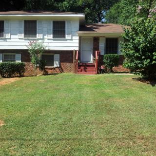 A suburban house with a well-maintained lawn and trees.