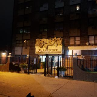 A view of a building at night, featuring a prominent banner and secure fencing.