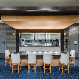 A modern restaurant interior with bar seating and ambient lighting.